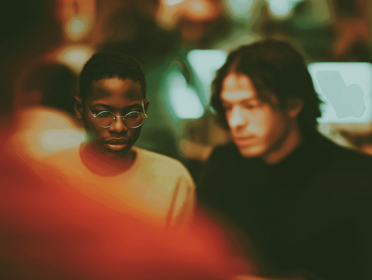 Two young men in soft focus inside a warmly lit studio